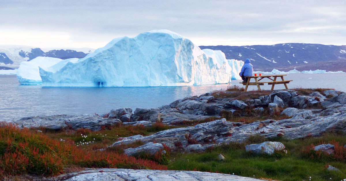 Groenlandia: donna che guarda un iceberg